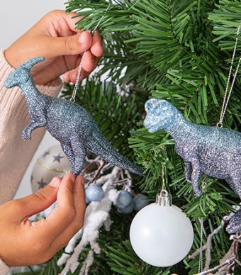 árvore de natal decorada com enfeites em forma de dinossauros, bolas brancas e bagas azuis 